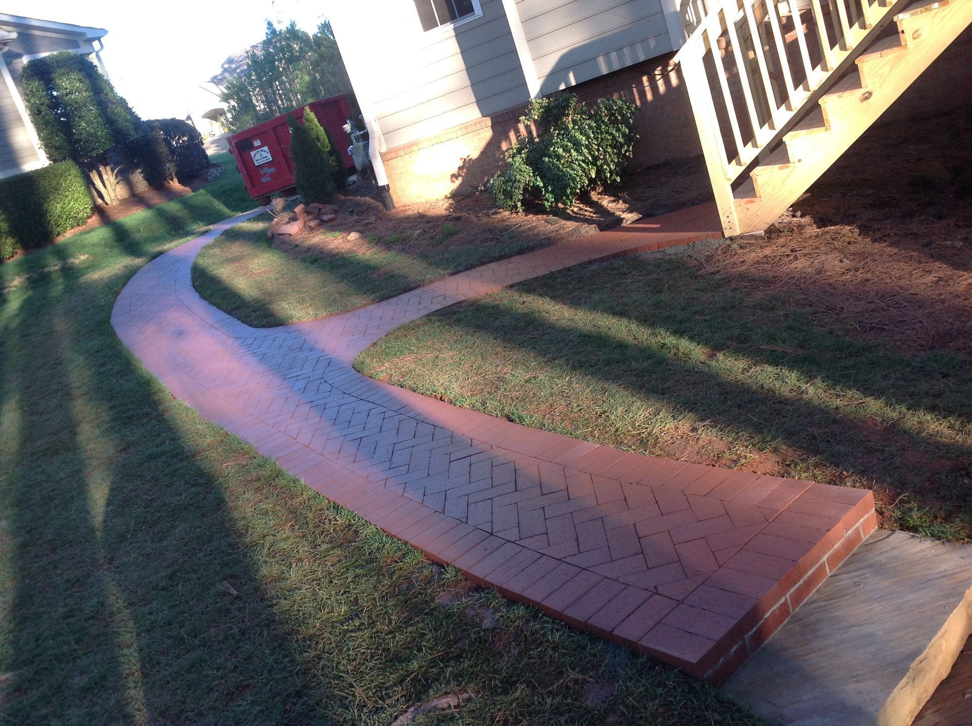 A brick walkway leading to a house with stairs