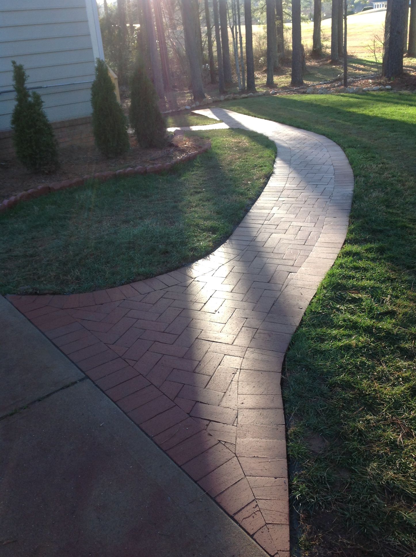 A brick walkway going through a lush green field