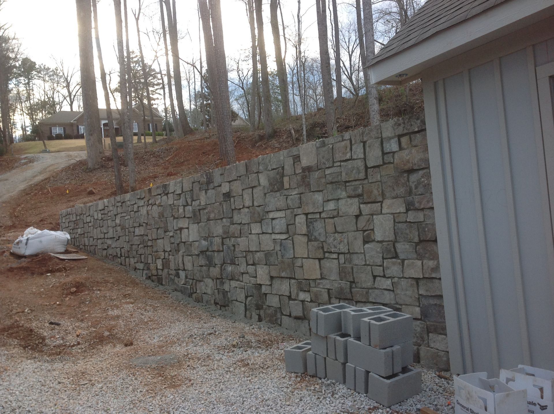 A stone wall is being built in front of a garage