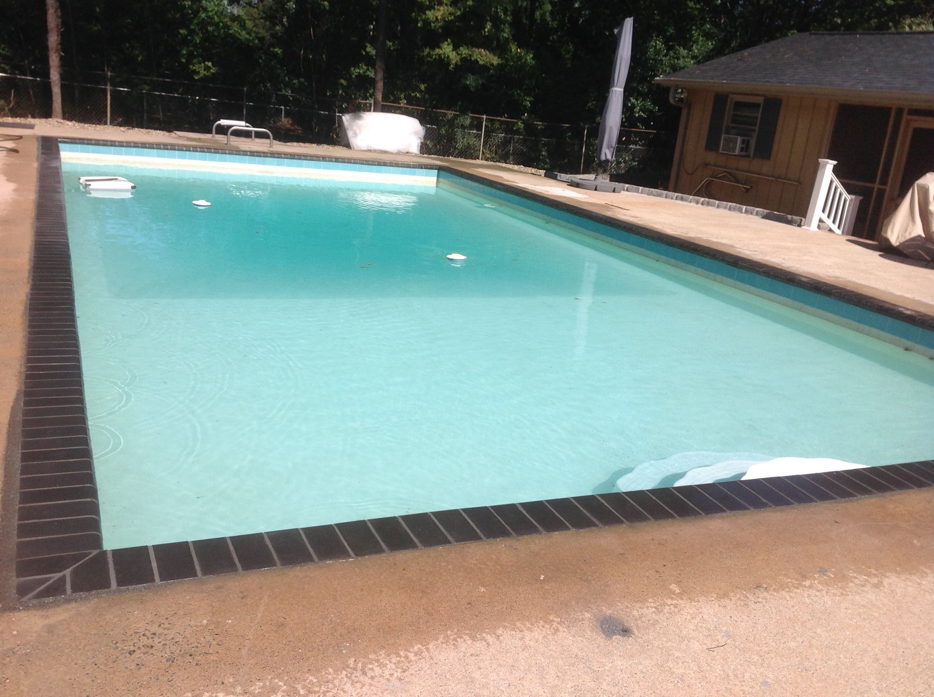 A large swimming pool with a house in the background