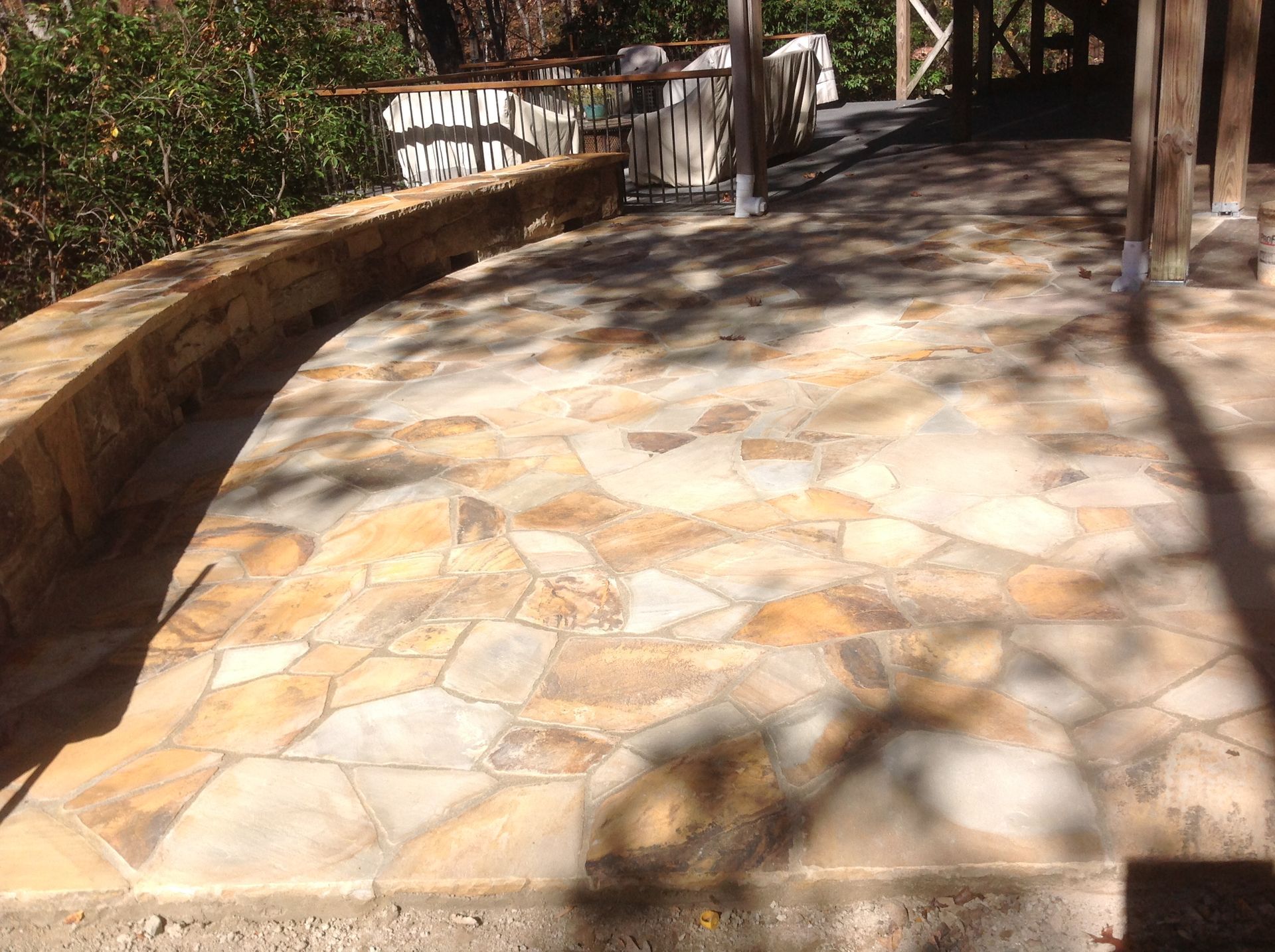 A stone walkway with a wooden railing and trees in the background