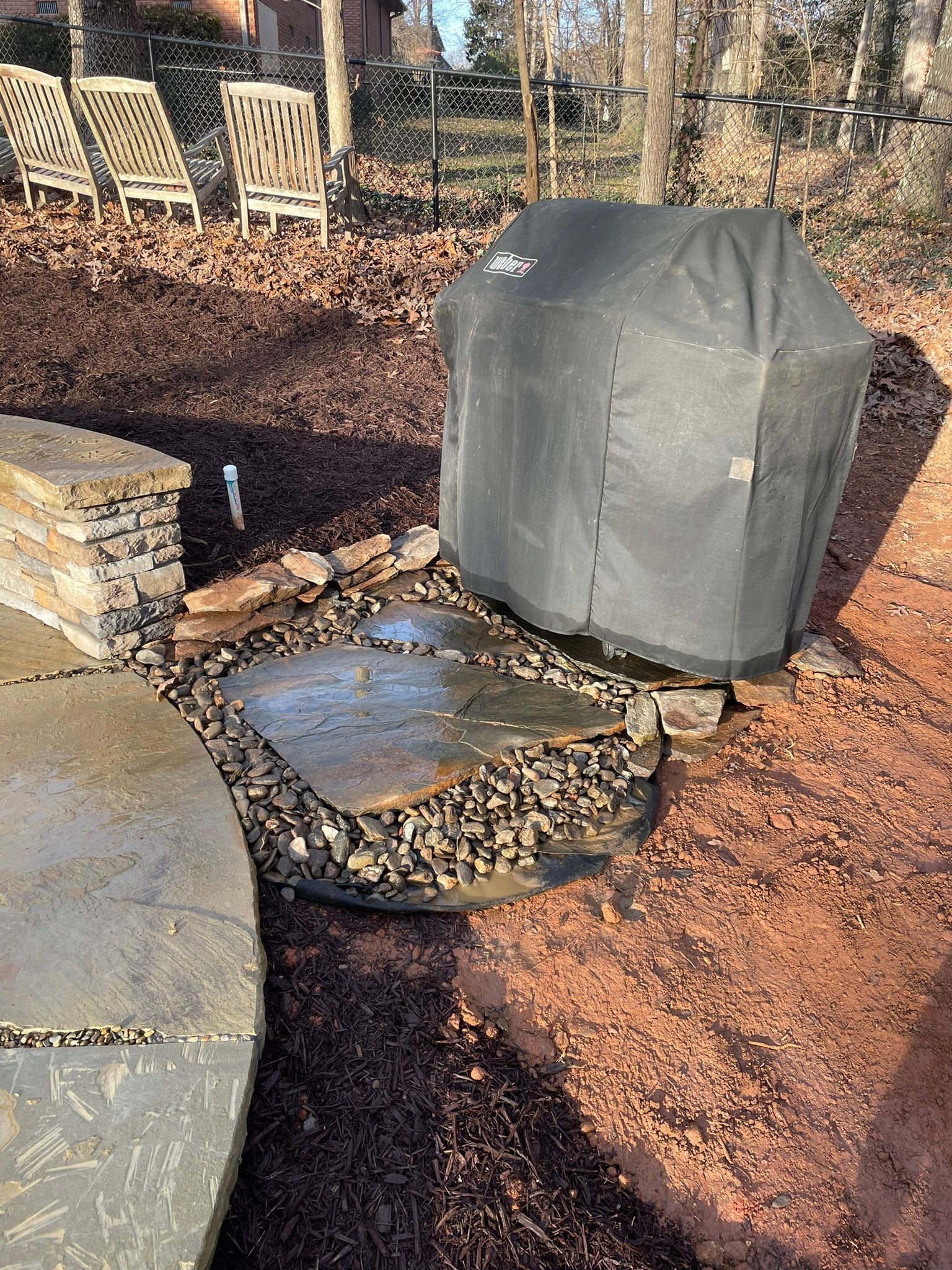 A grill with a cover on it is sitting on top of a rock.