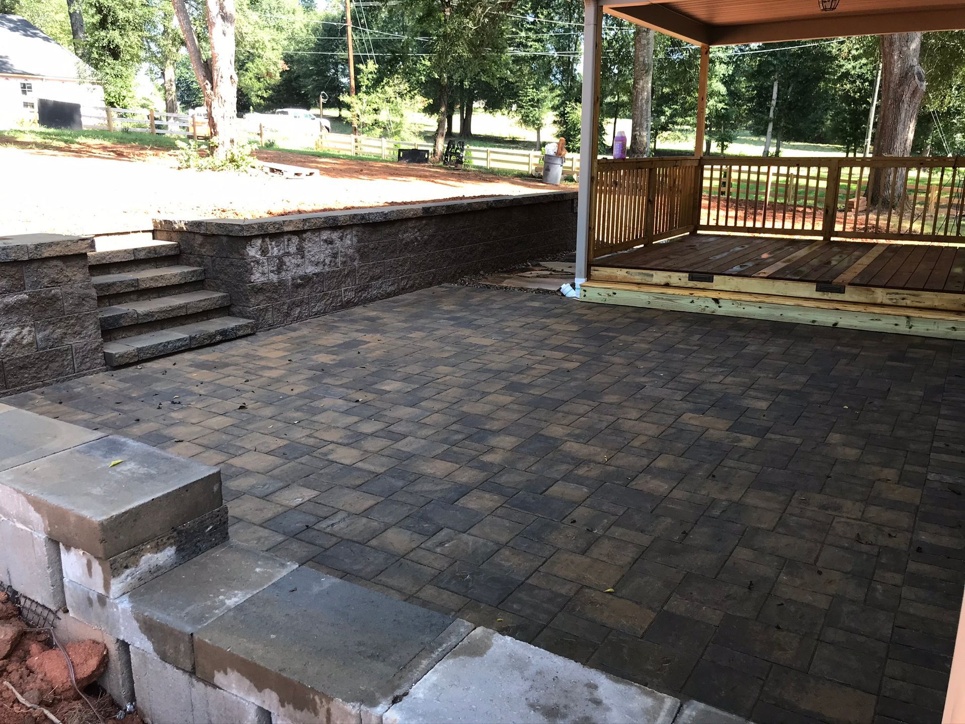 A brick patio with stairs and a wooden deck under a canopy.