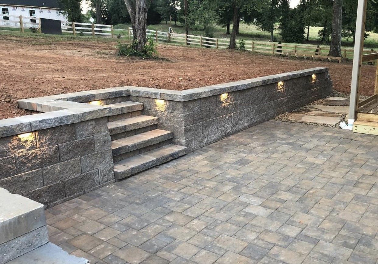 A stone wall with stairs leading up to a patio.