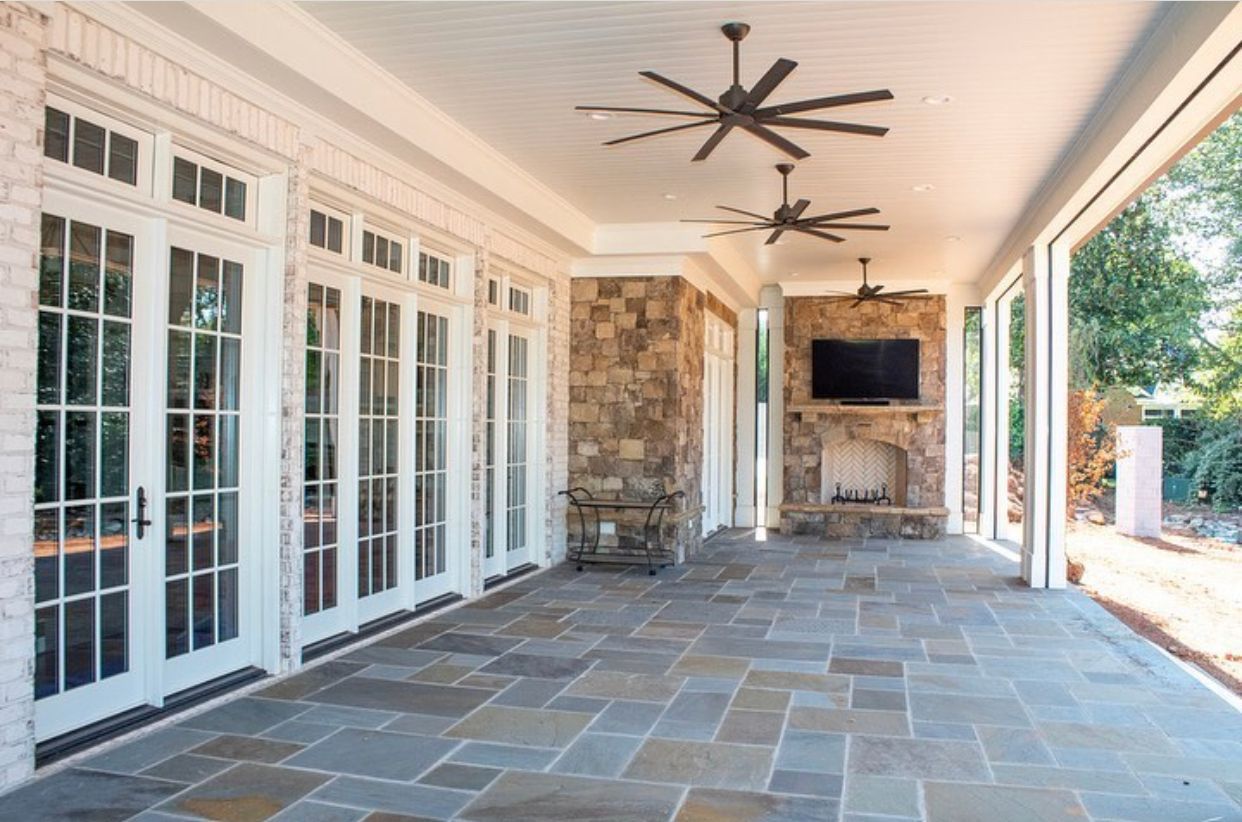 A large covered patio with a fireplace and ceiling fans.
