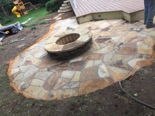 A fire pit is sitting in the middle of a stone patio.
