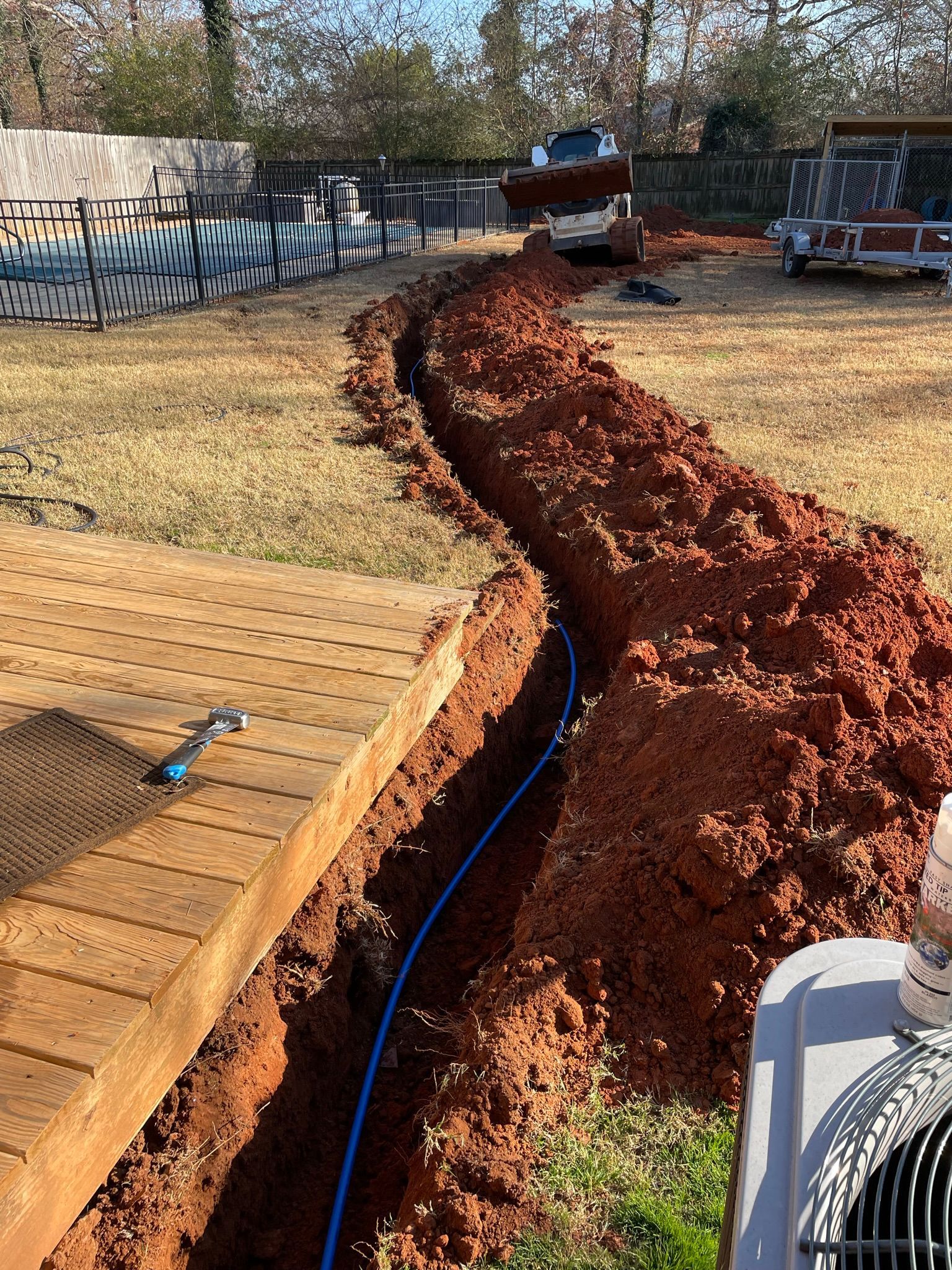 A person is digging a hole in the ground next to a fan.