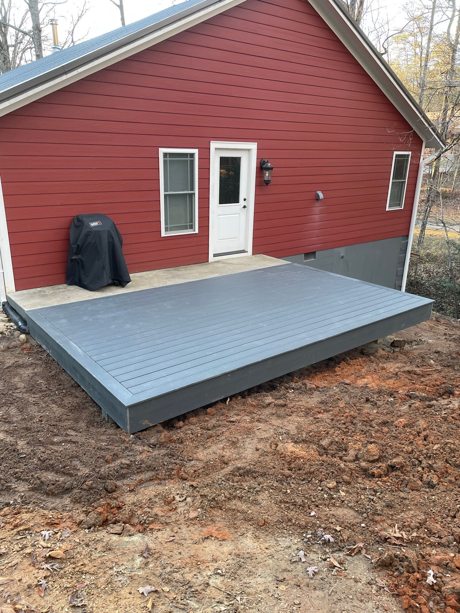 A red barn with a gray deck in front of it.