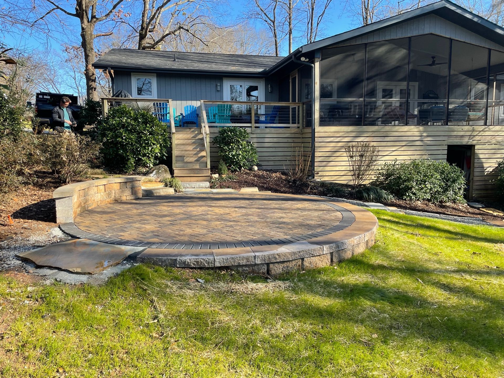 A house with a screened in porch and a patio in front of it.