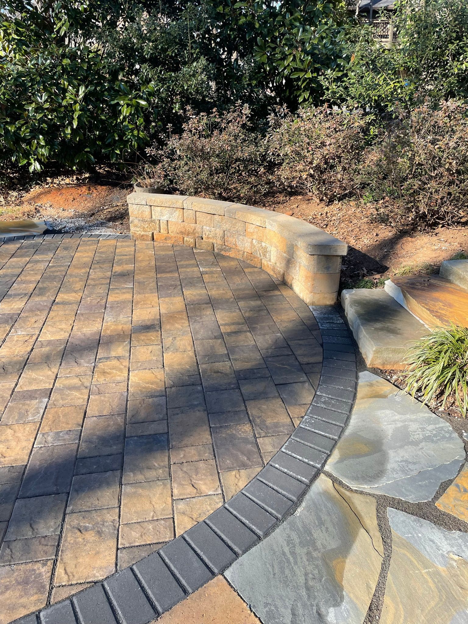A walkway with a stone wall and trees in the background.