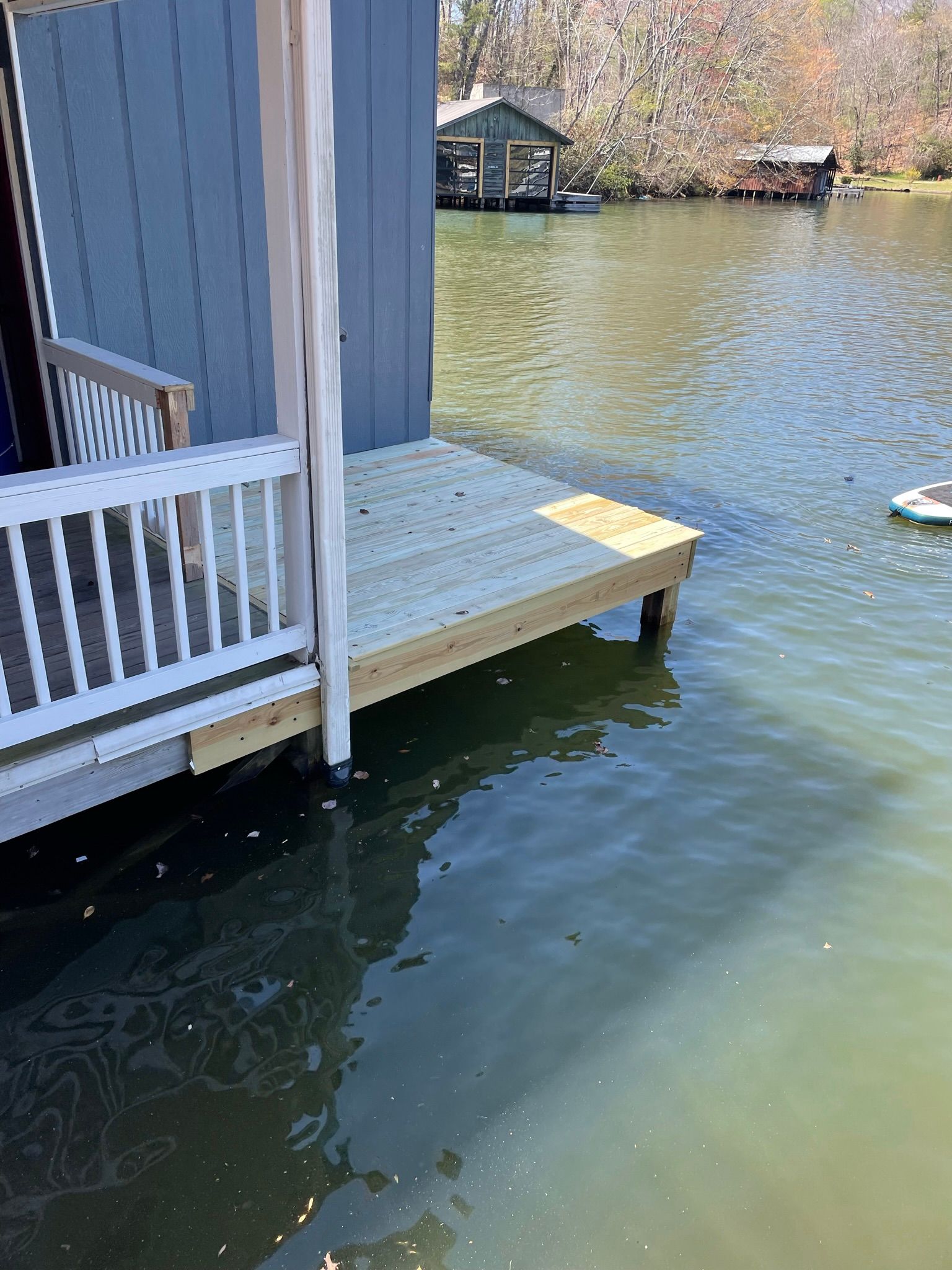 A dock with a white railing is next to a body of water.