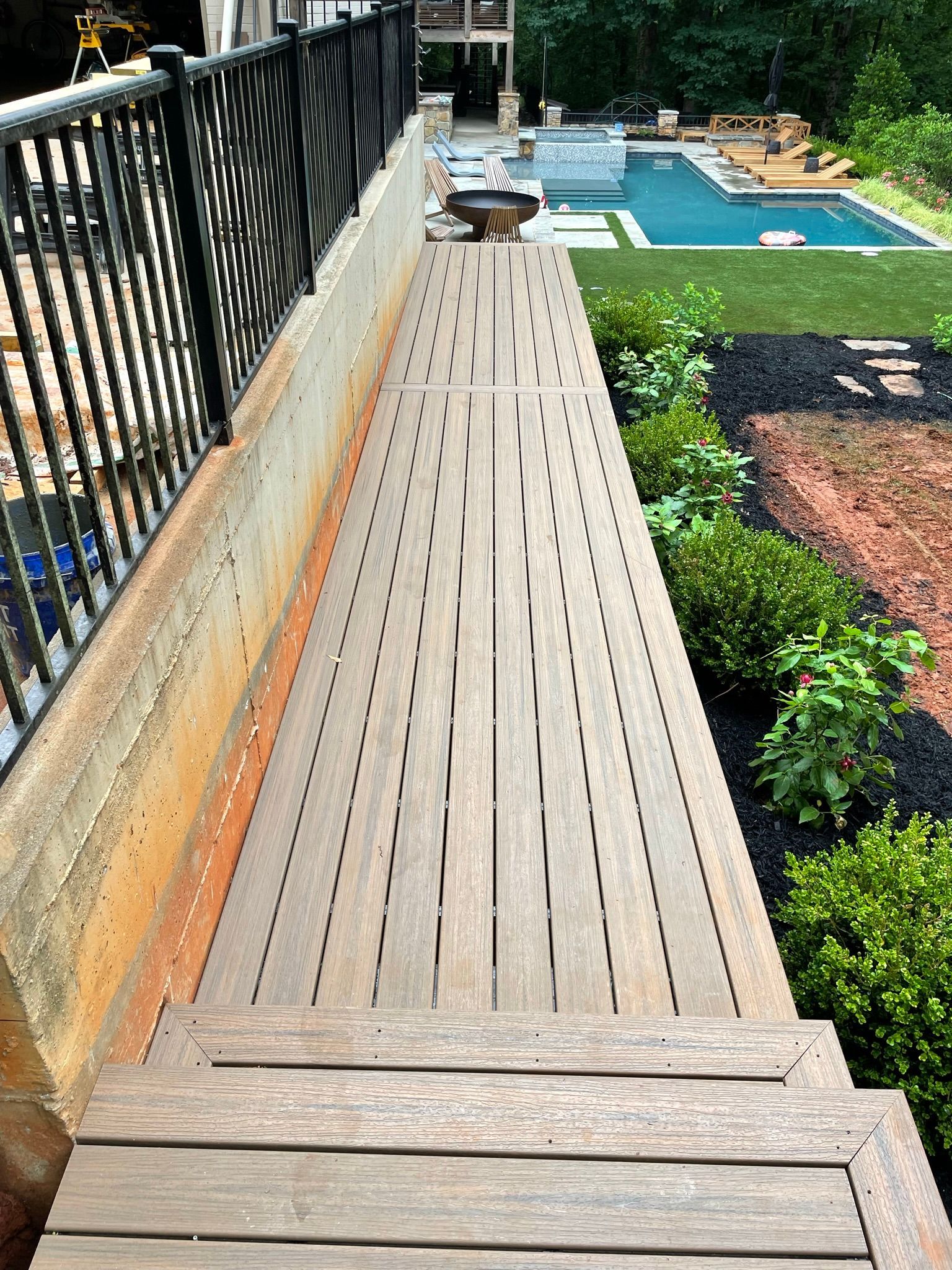 A wooden walkway leading to a swimming pool in a backyard.