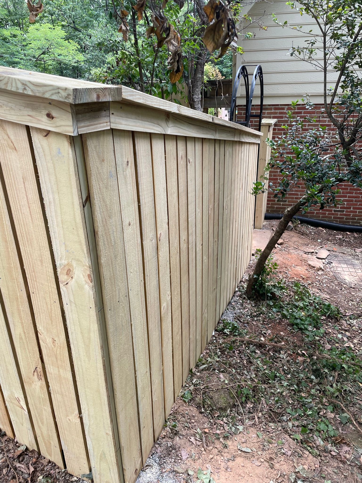 A wooden fence is in the backyard of a house.