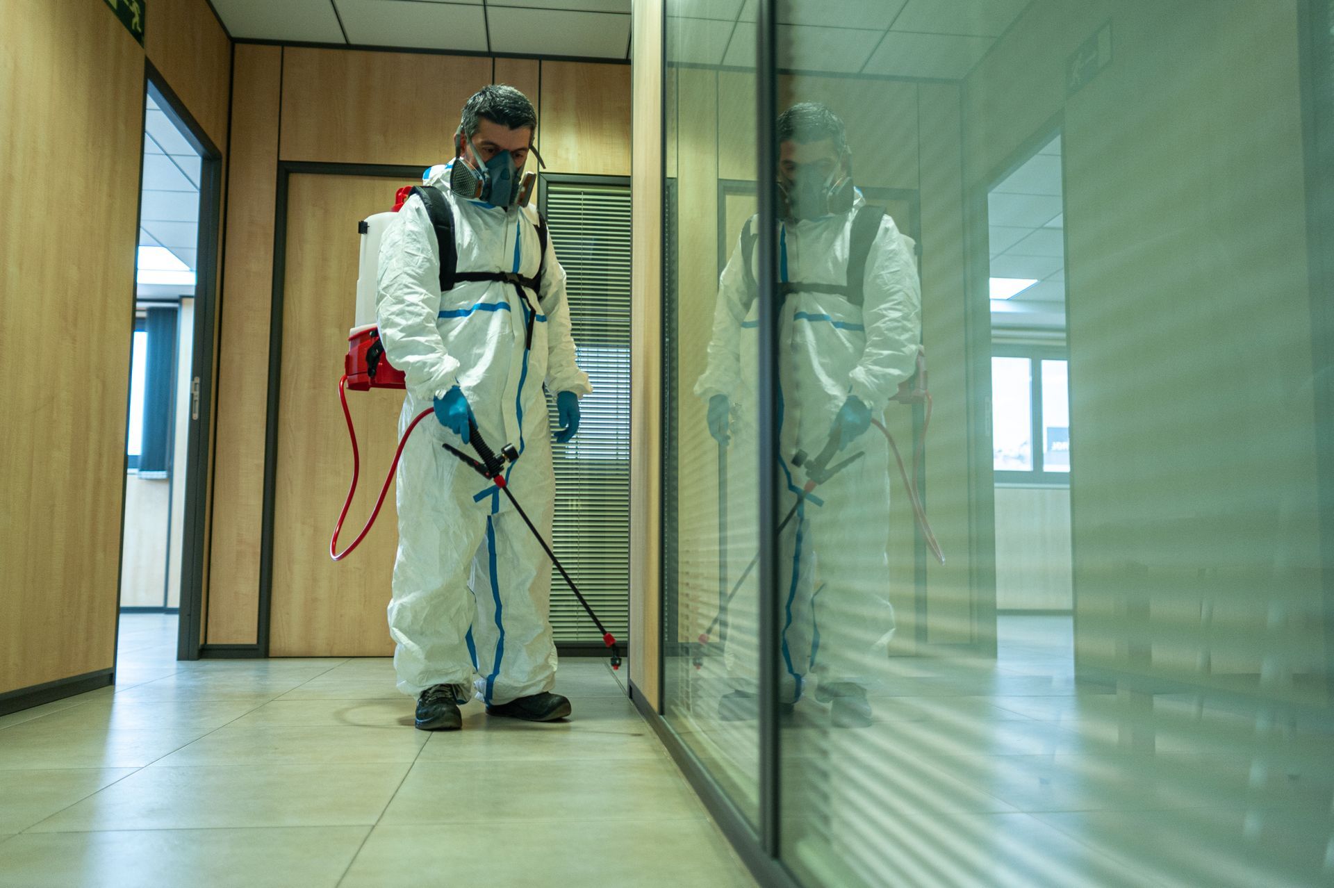 Commercial pest control technician applying treatment in an office building.