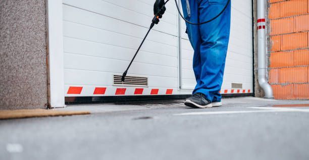 Manual worker disinfecting underground garage, showcasing pest exterminator safety services.