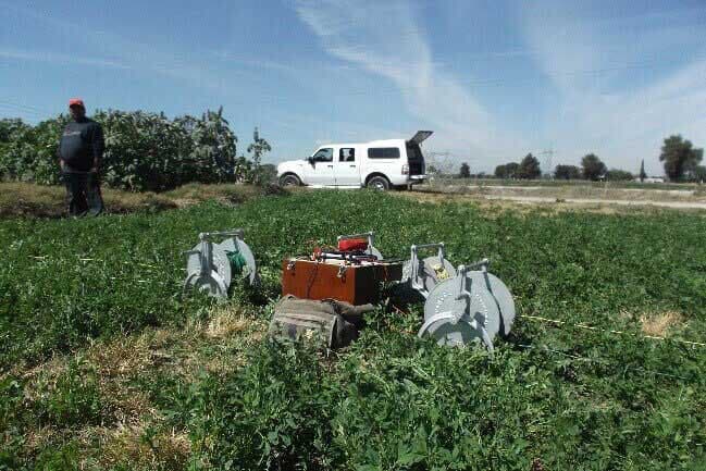 Campo con equipo científico, un camión y una persona.