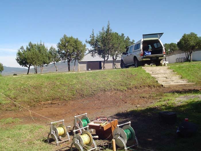 Equipo de reconocimiento cerca de un camión en una colina cubierta de hierba, posiblemente para investigación científica.