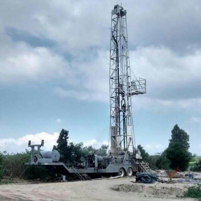 Plataforma de perforación sobre ruedas en un campo bajo un cielo nublado.