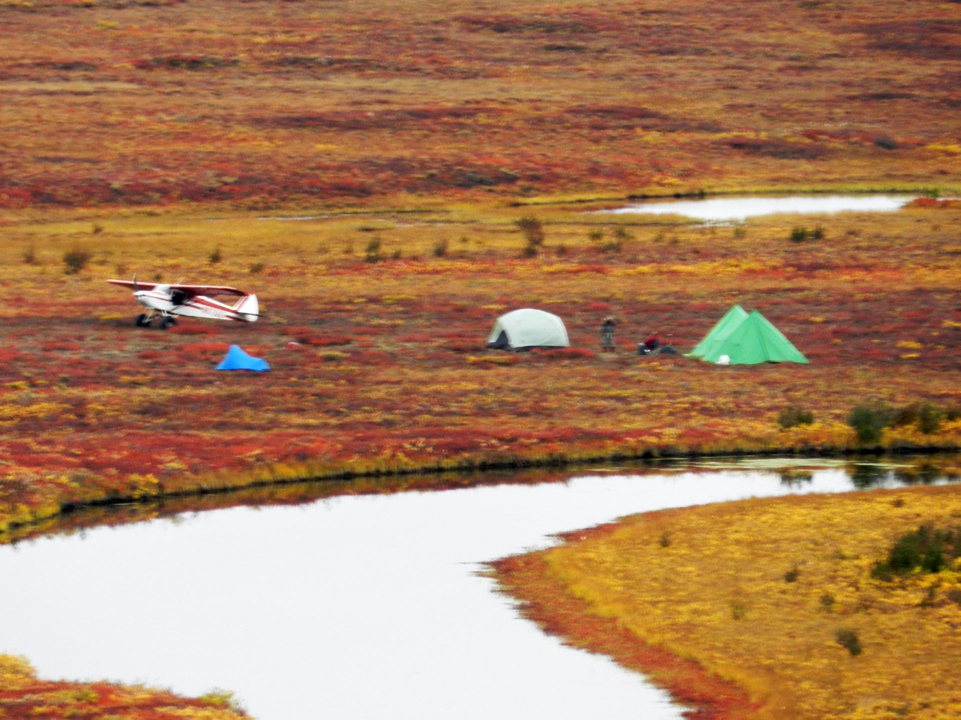 A small plane is parked in the middle of a field next to a river