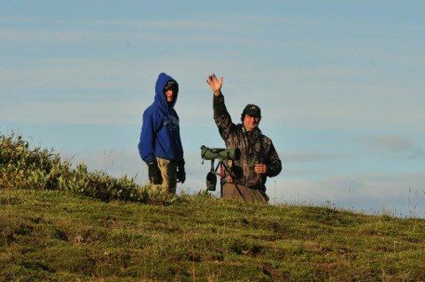 Two people are standing on top of a grassy hill.