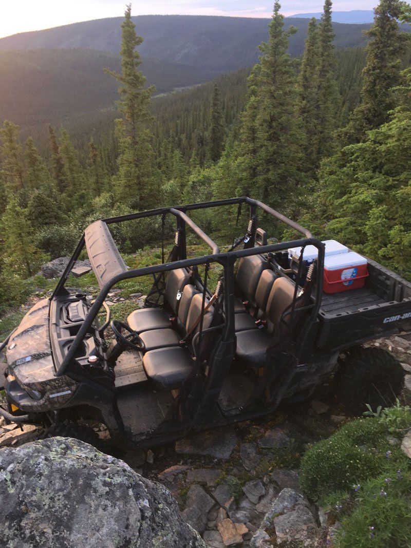A four wheeler is parked on top of a rocky hill in the woods.