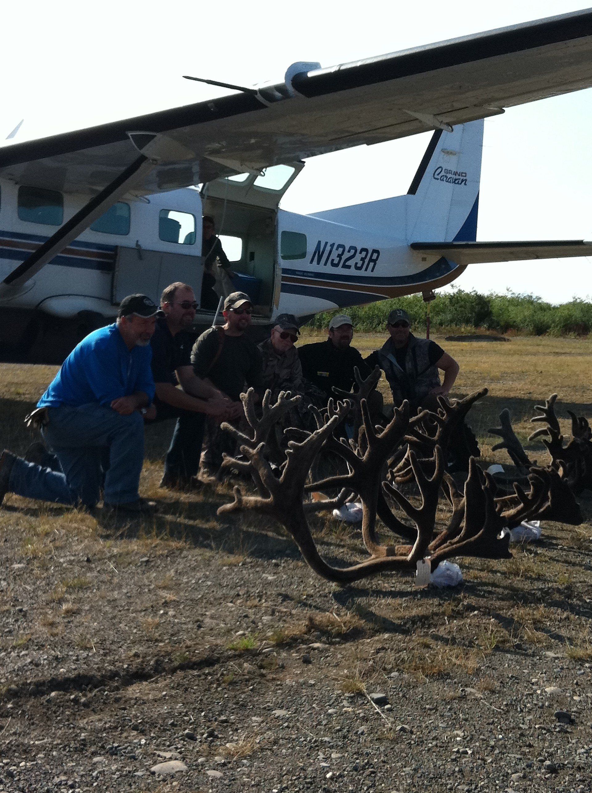  caribou hunters posing with their trophies in front of a plane in the arctic