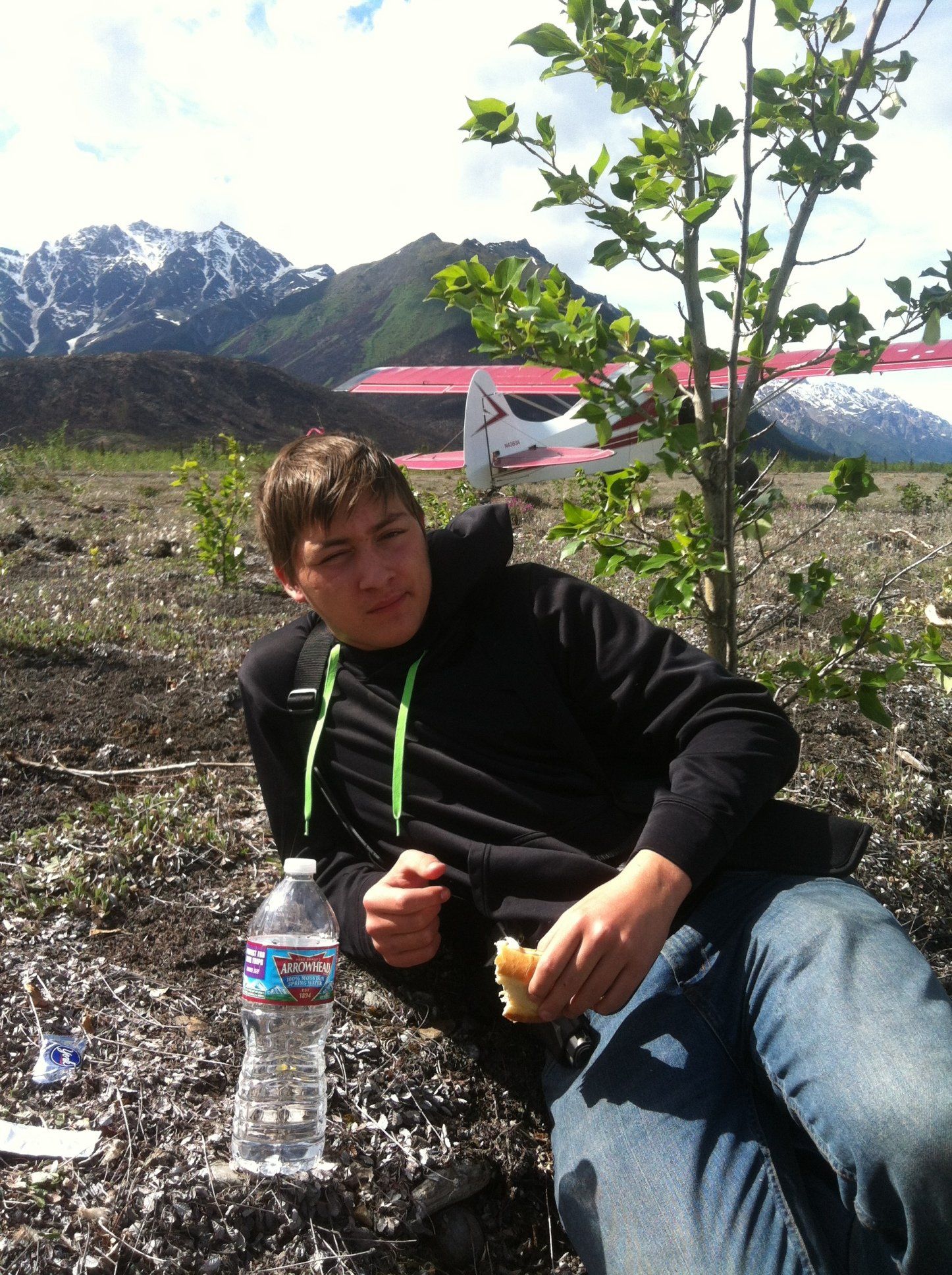 A man sits on the ground with a bottle of aquafina water