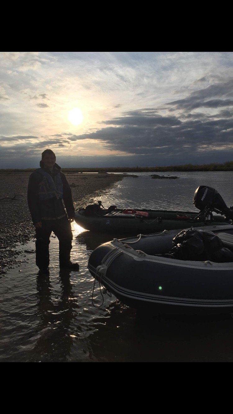 A man is standing in the water next to a boat.