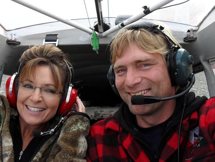 A man and a woman wearing headphones in a plane