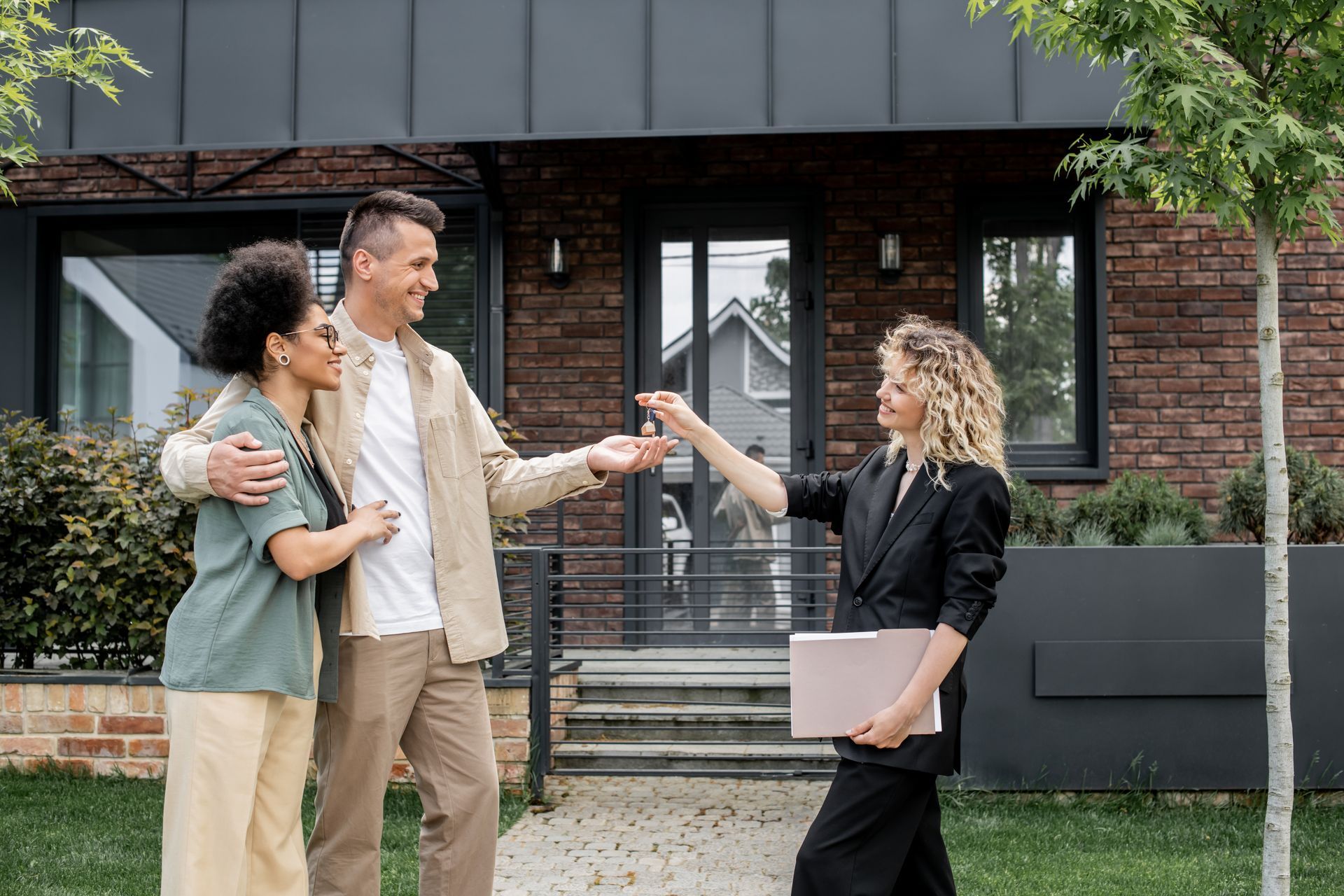 Racquel Wilder Realty clients standing in their doorway with a custom welcome mat at their new home.