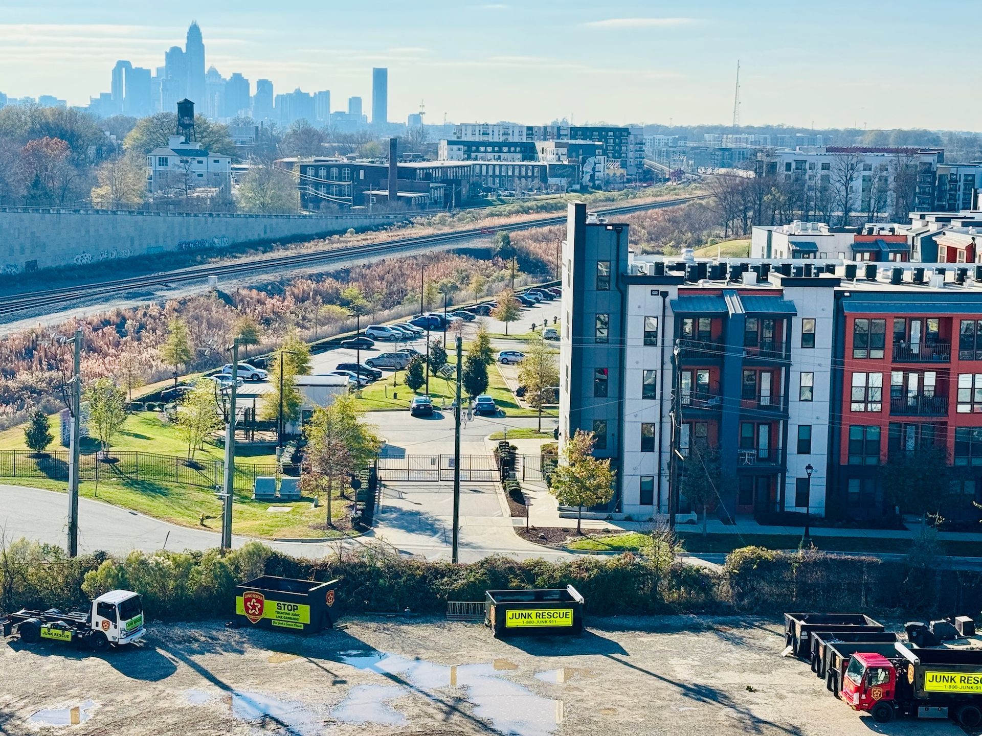 View of a city skyline with apartment buildings, a railroad track, and construction vehicles.