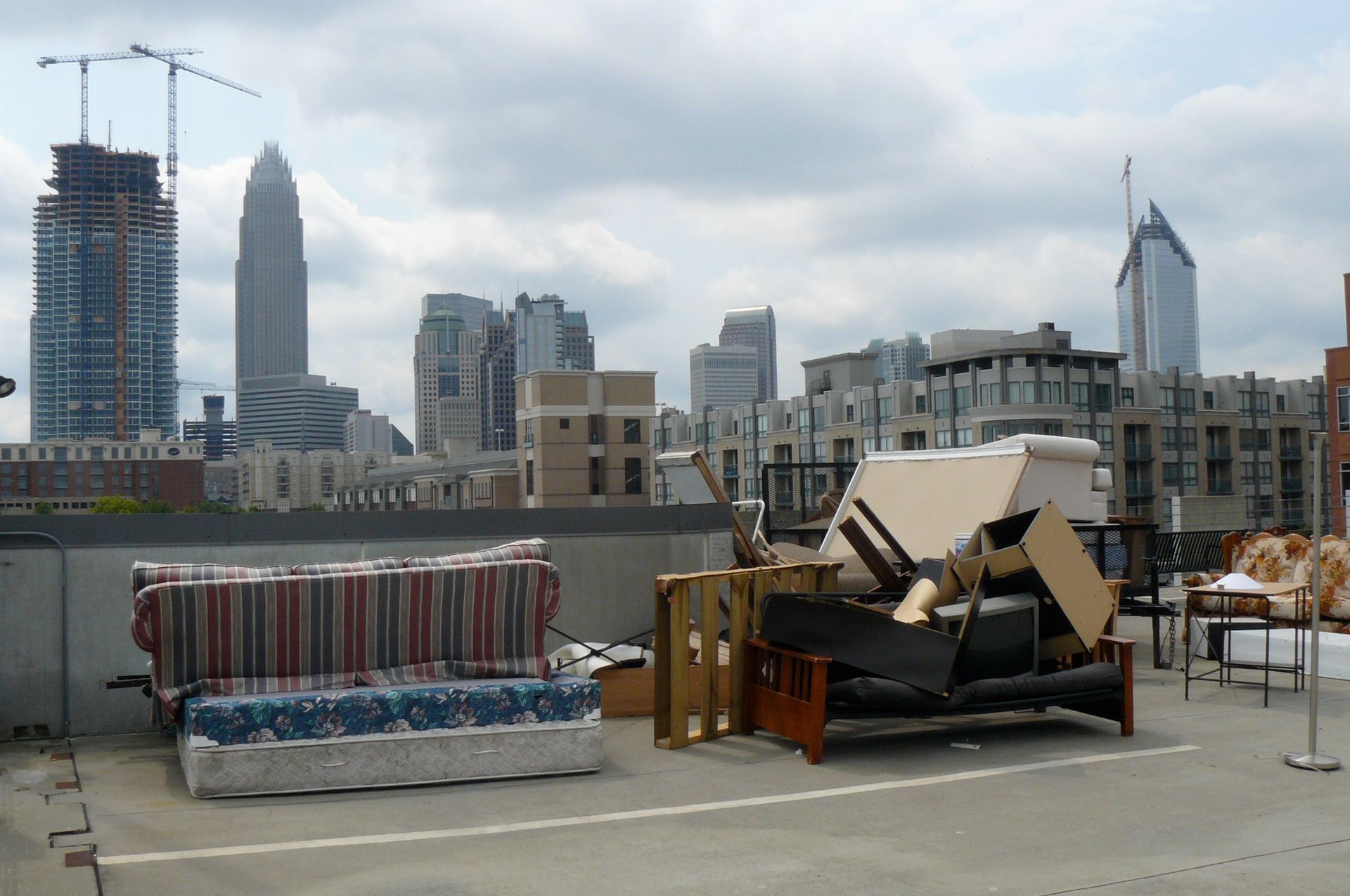 Rooftop with discarded furniture, Charlotte skyline in background.