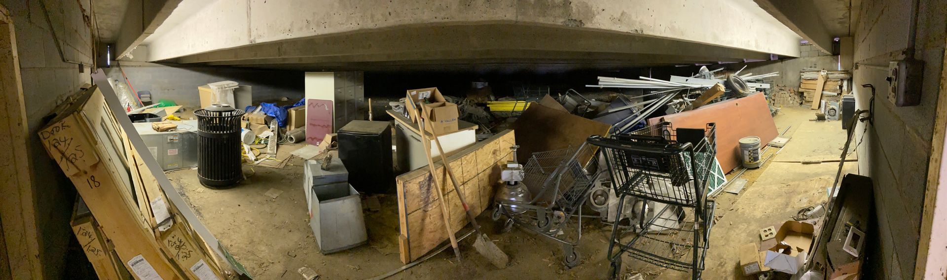 An under-bridge space cluttered with various objects.