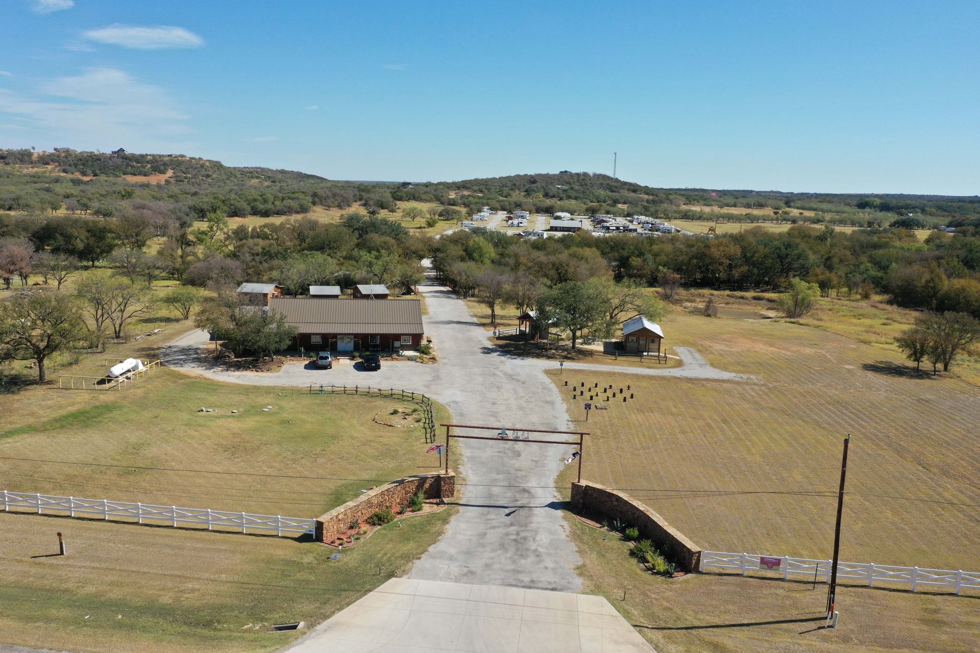 An aerial view of a dirt road leading to a house in the middle of a field.