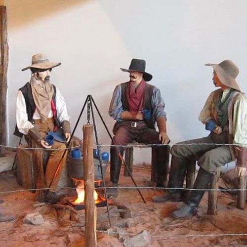 A group of cowboys are sitting around a campfire
