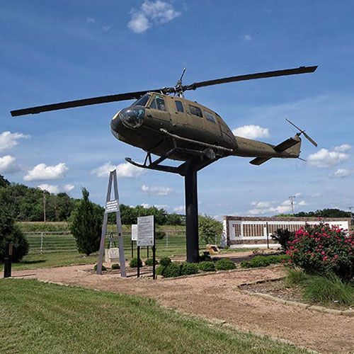 A large military helicopter is on display in a park