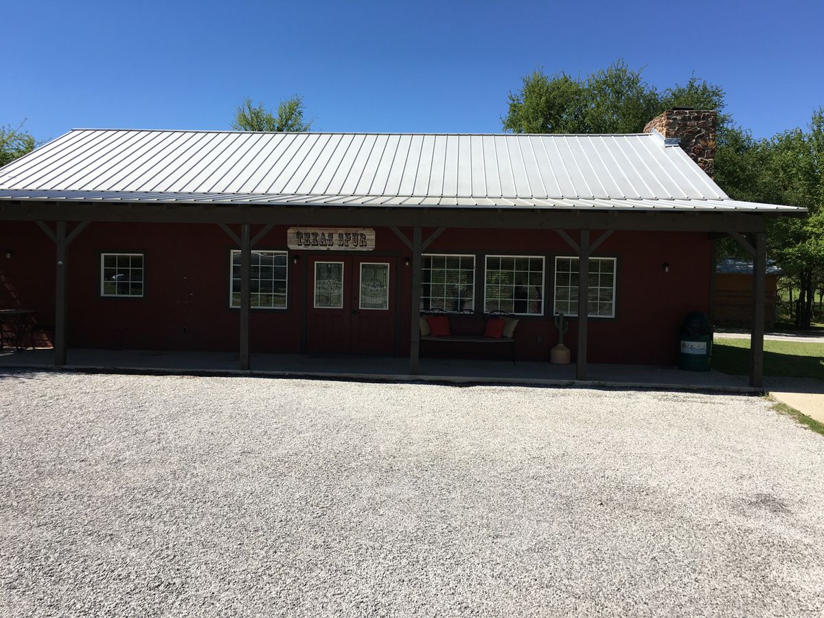 A red building with a white roof is sitting on top of a gravel lot.