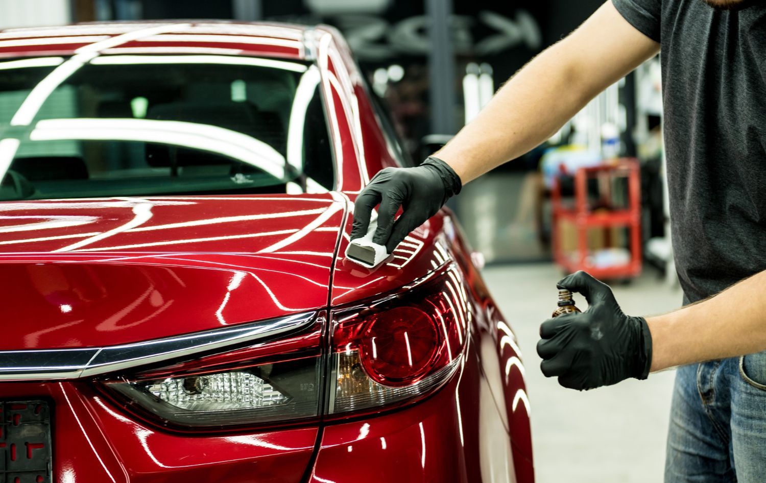 A man is polishing a red car in a garage.