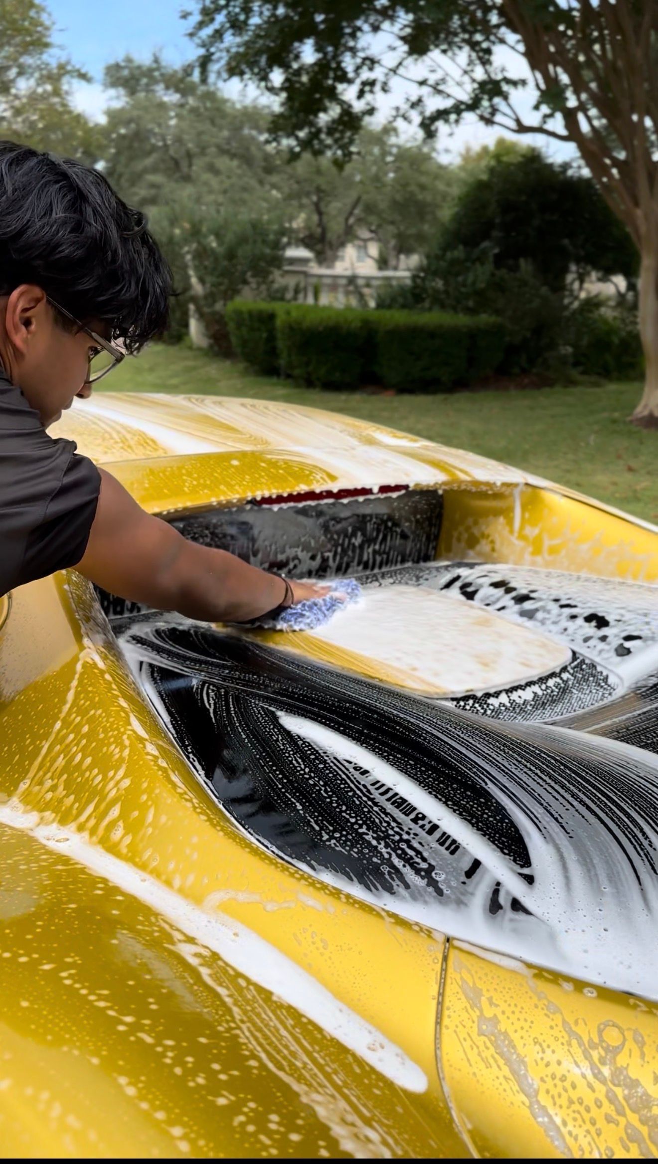 Person in black gloves applying ceramic coating to a car's dark gray paint.