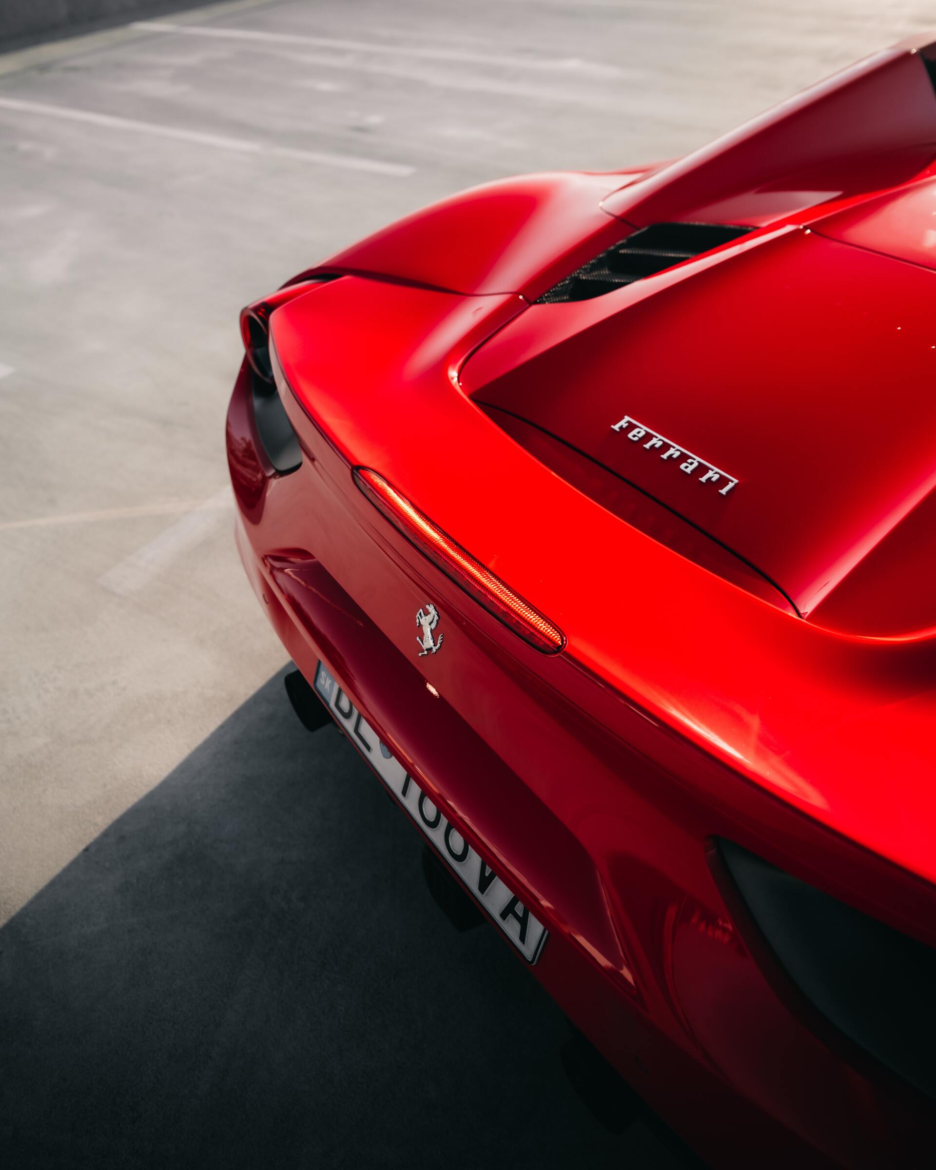 Rear view of a red Ferrari sports car with a spoiler parked on pavement