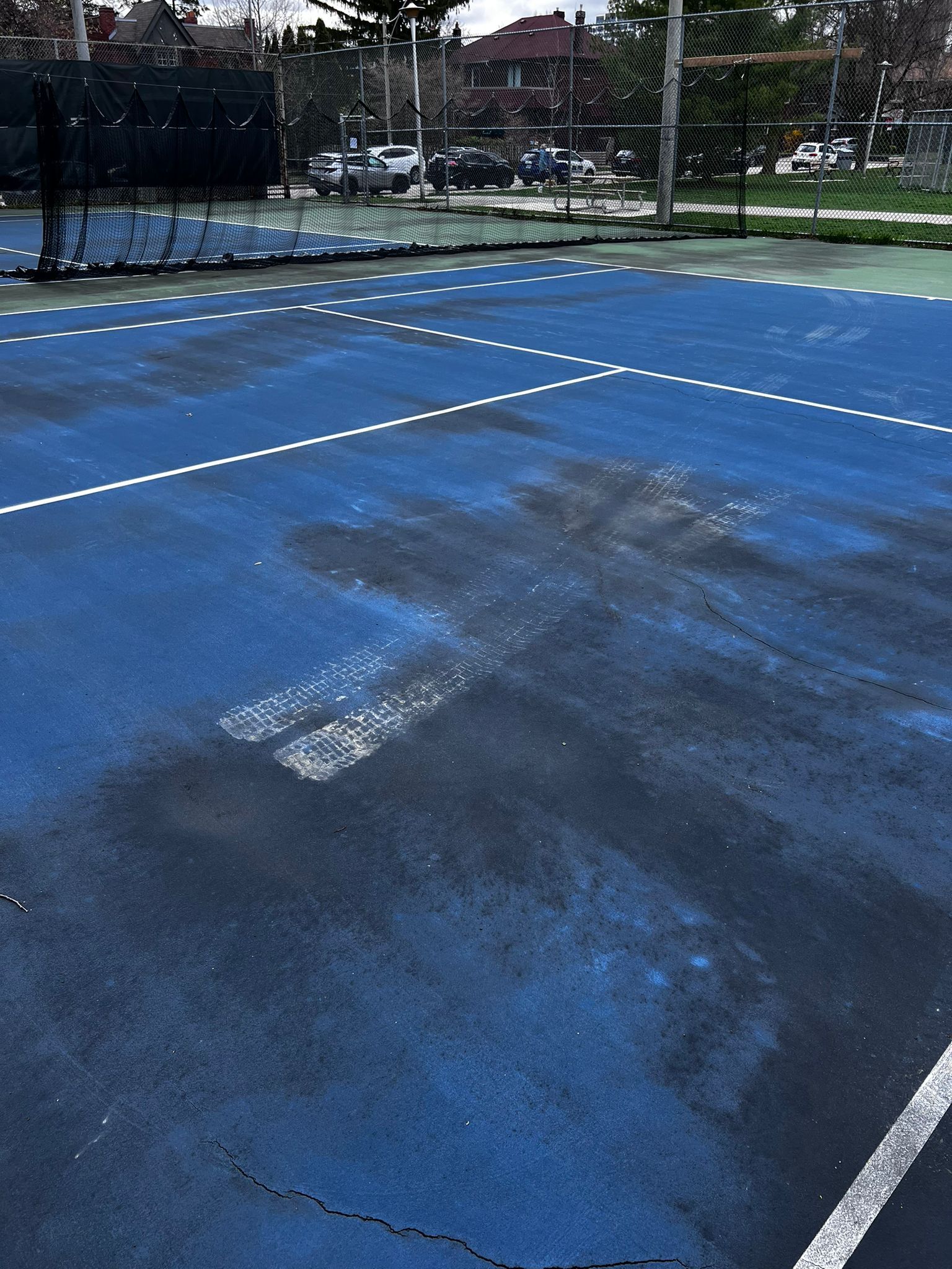 Blue tennis court with white lines and net in background.