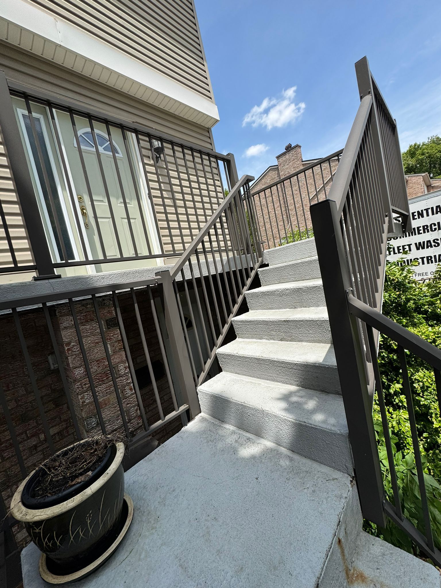 Exterior staircase with gray steps and brown railings, leading up to a door.