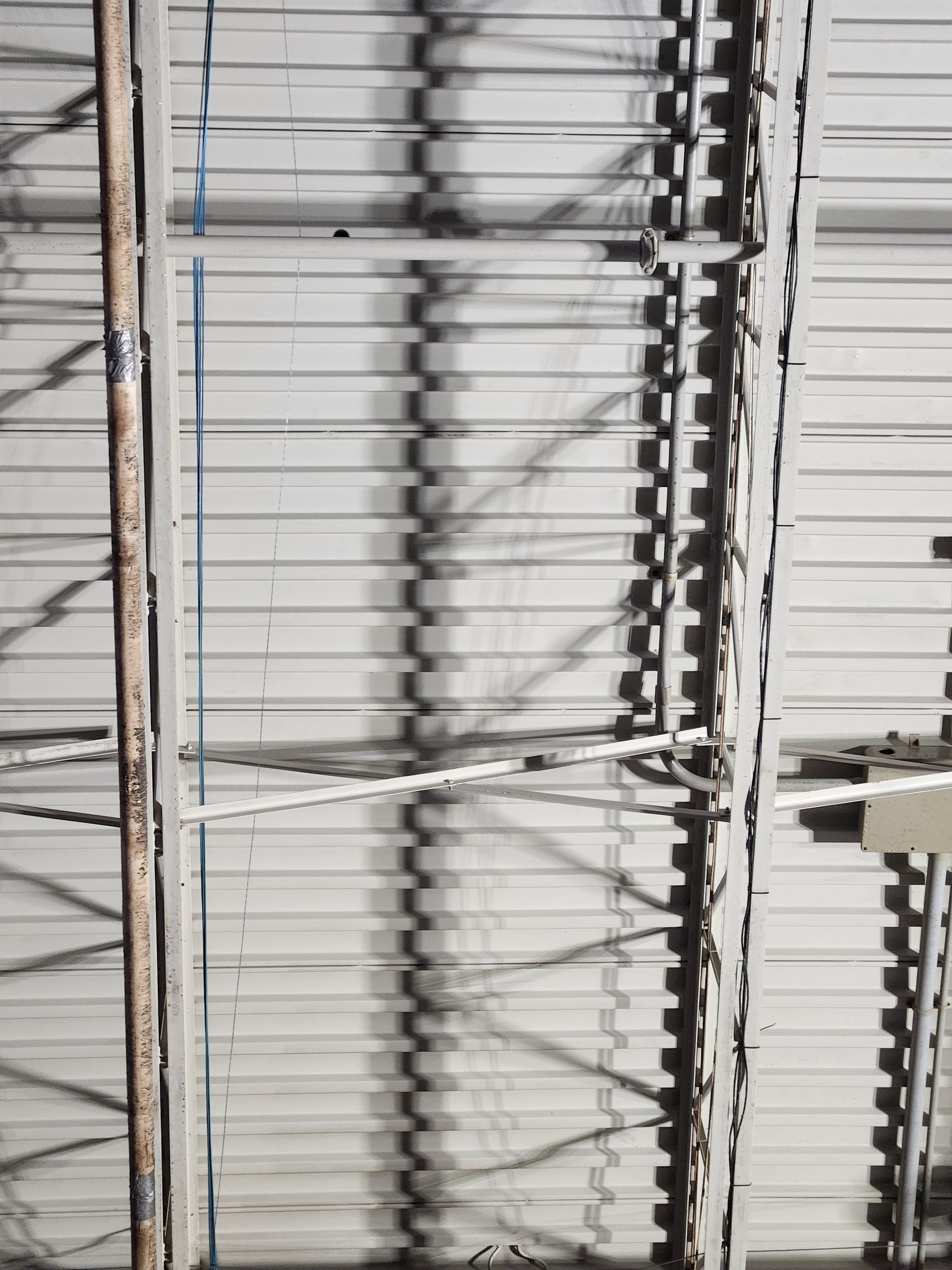 Industrial metal roof with support beams casting shadows.