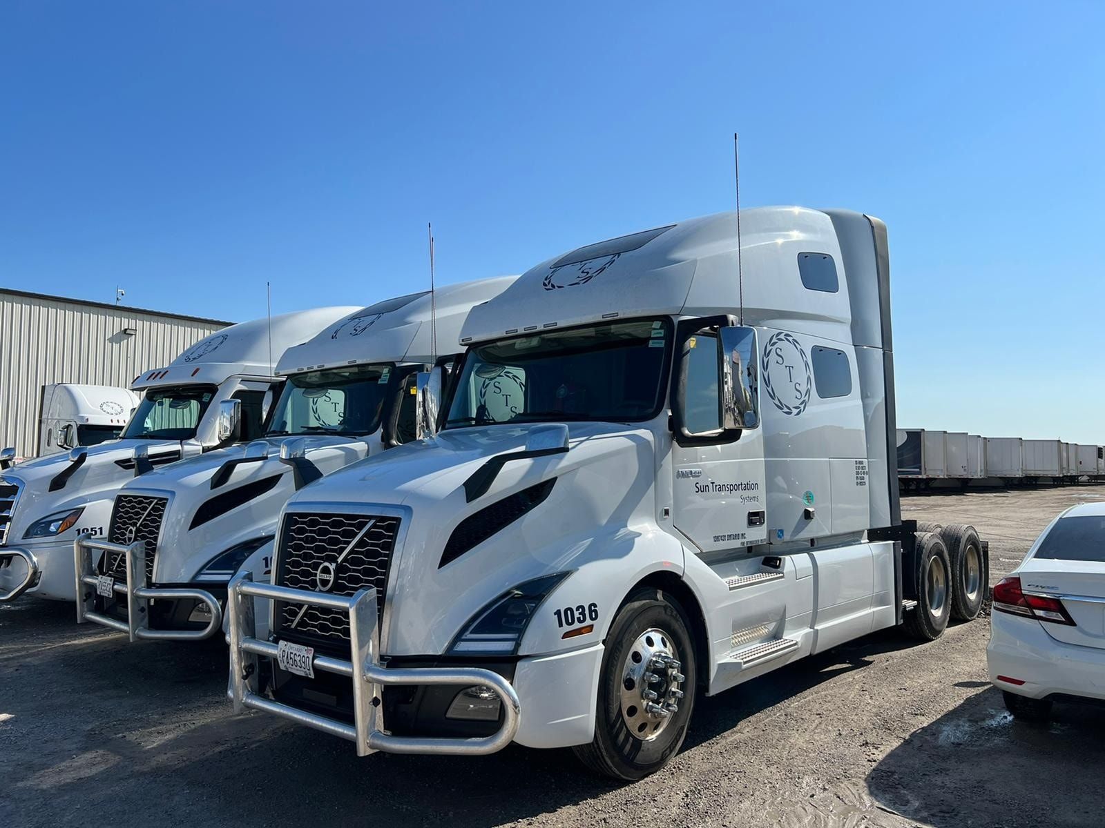 White semi-trucks parked outdoors on a sunny day.