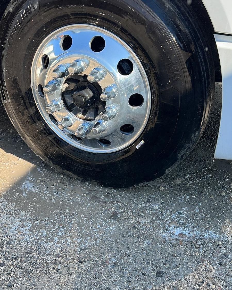 Shiny chrome truck wheel and tire on a gravel surface.