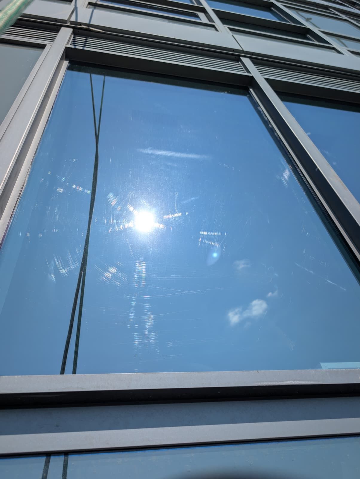 Blue sky and sun reflected in the windows of a modern building.