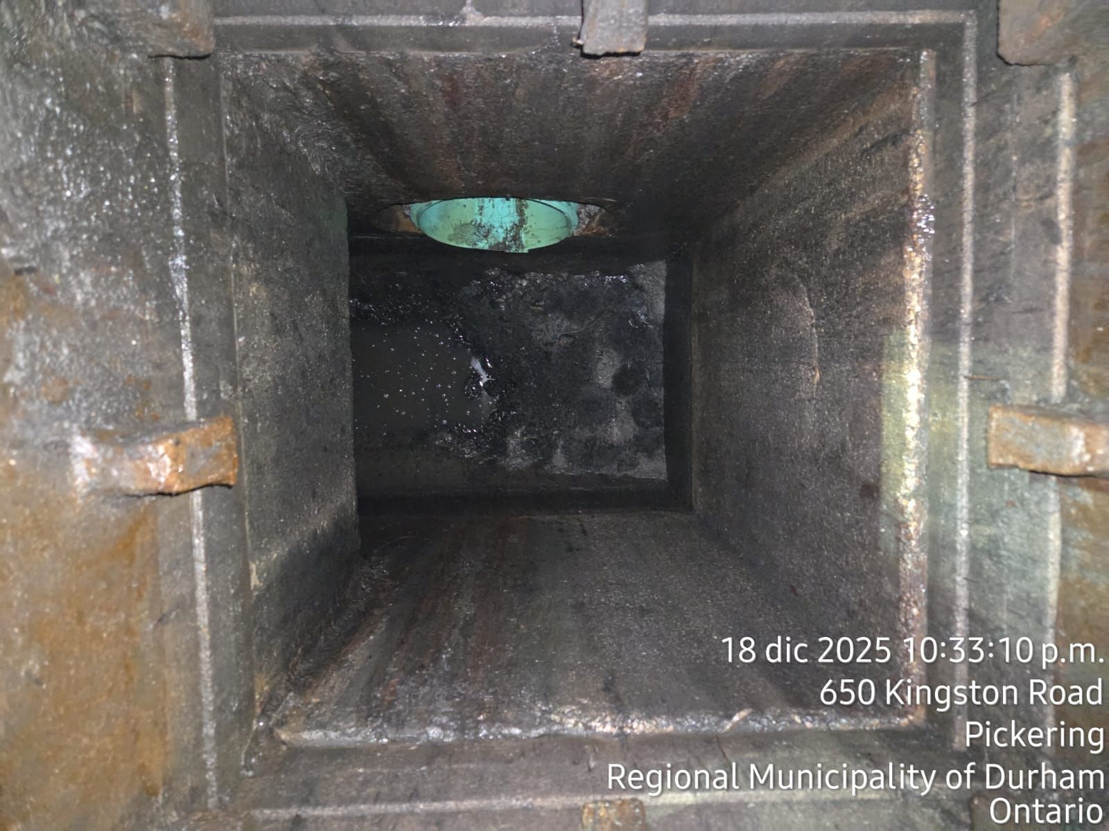 Interior view of a rectangular, dark, possibly metal, shaft. The date and location are visible at the bottom.