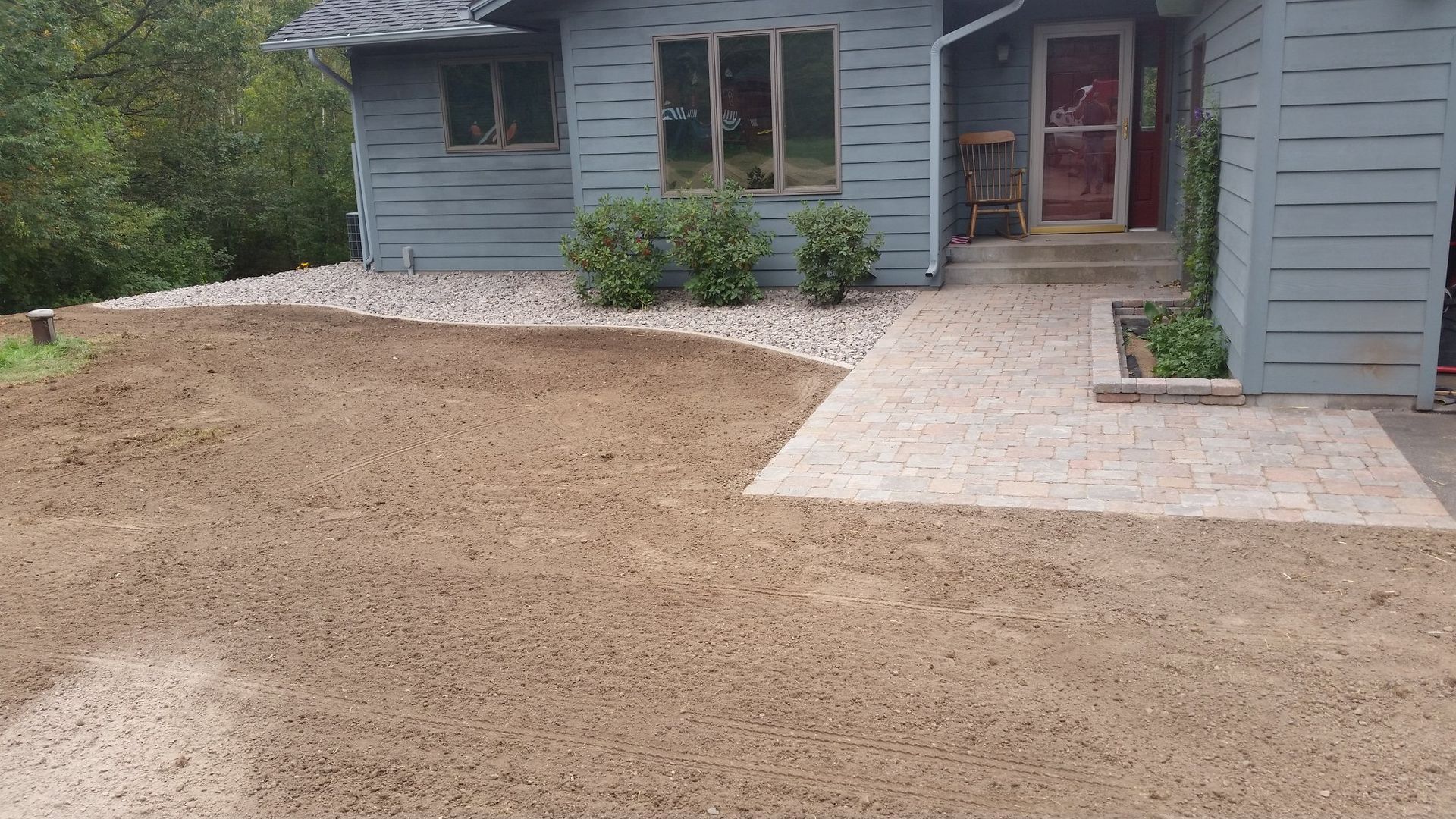 House exterior with concrete path, gravel border, and freshly turned earth.