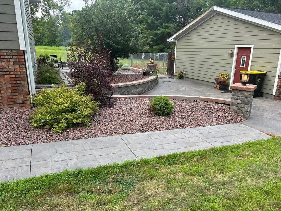 A gravel-filled enclosure next to a wooden hot tub and a brown building. W