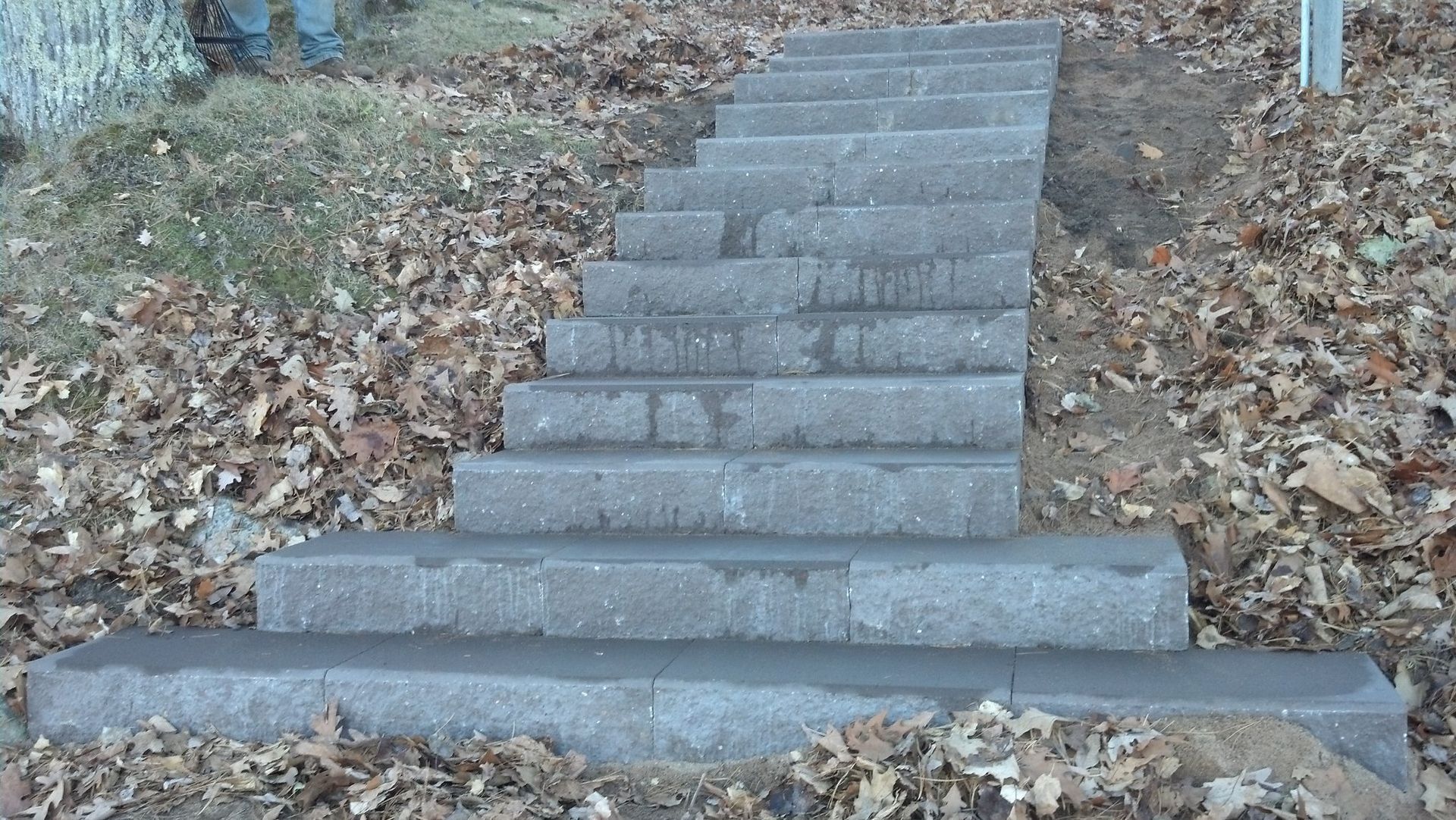 Stone steps leading up a grassy hill, covered with autumn leaves.